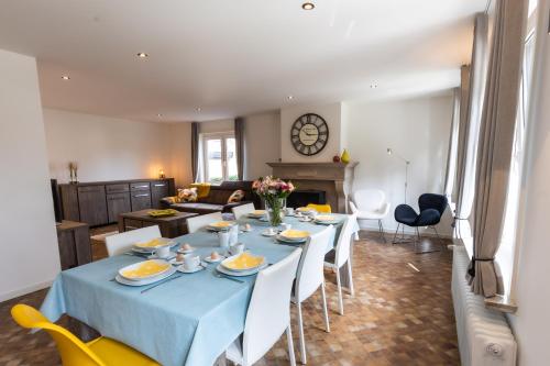 a dining room and living room with a blue table and chairs at Aan de bosrand in Oudsbergen 