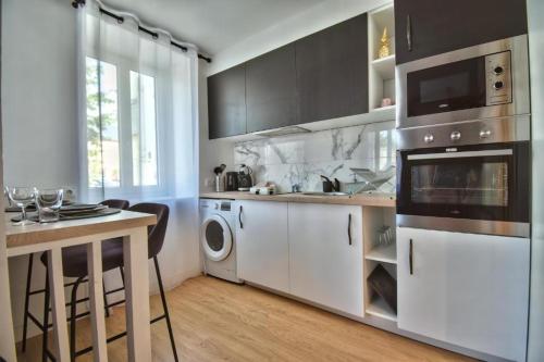 a kitchen with white cabinets and a sink and a dishwasher at Le Cocon de Maintenon in Maintenon