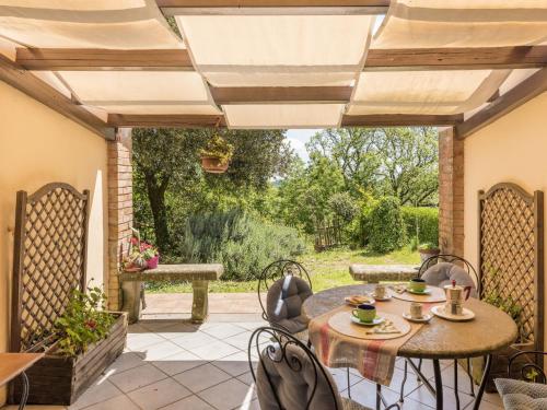 a patio with a table and chairs with a view of a garden at Holiday Home Allumiere by Interhome in Allumiere
