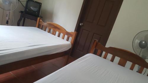 a bedroom with two beds and a tv and a door at Hostal El Jardin in León