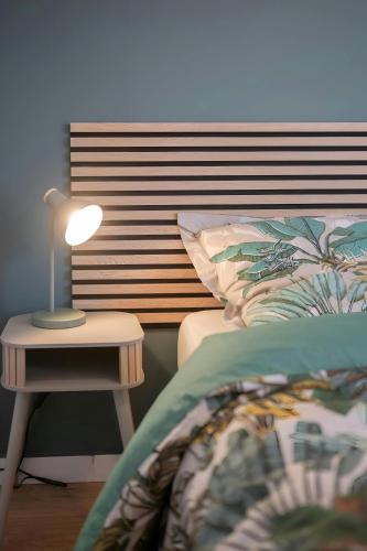 une chambre avec un lit et une table avec une lampe dans l'établissement LEntre Deux : havre de paix entre nature ville, à Rodez