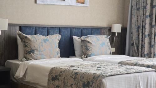 two beds in a bedroom with blue walls and pillows at Hill Park Gusar in Qusar