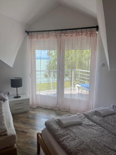 a bedroom with a bed and a large window at Beach Resident in Balatonszemes