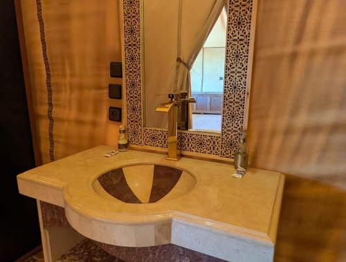 a bathroom with a sink and a mirror at Amkrane luxury camps in Merzouga