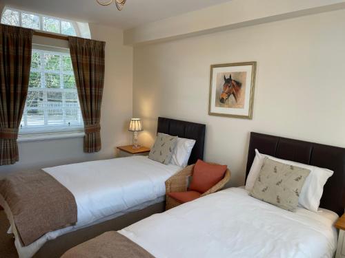 a bedroom with two beds and a chair and a window at The Towerview Coach Houses in Perth