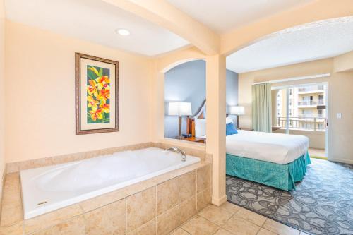 a hotel room with a tub and a bed at Vacation Village at Parkway in Orlando