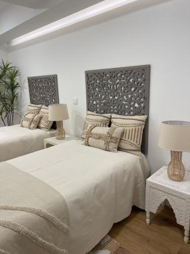 a white bedroom with two beds and two lamps at Happy Stork Tróia Beach Flat in Troia