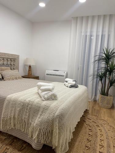 a white bedroom with a bed with towels on it at Happy Stork Tróia Beach Flat in Troia