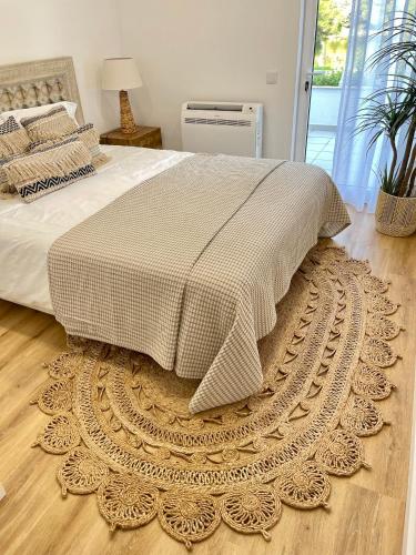 a bedroom with a bed and a rug on a wooden floor at Happy Stork Tróia Beach Flat in Troia