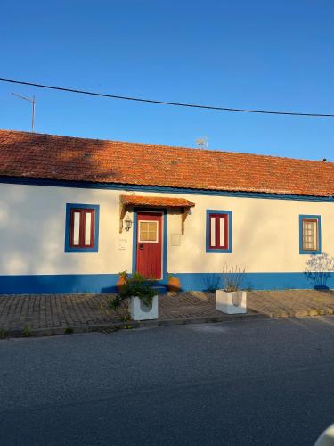 a white house with a red door on a street at Happy Stork Tróia Beach Flat in Troia