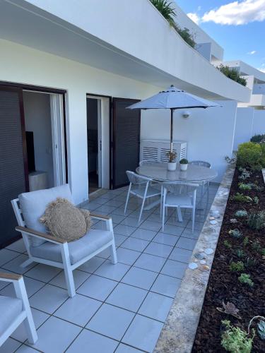 a patio with a table and chairs and an umbrella at Happy Stork Tróia Beach Flat in Troia