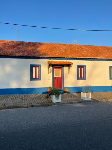 a house with a red door on a street at Happy Stork Tróia Beach Flat in Troia