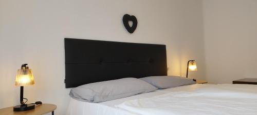 a white bed with a black headboard and a clock on the wall at Appartamento Novecento in Enguiso