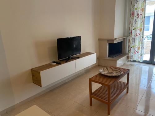 a living room with a flat screen tv and a table at Sofia's Apartment in Nea Moudania