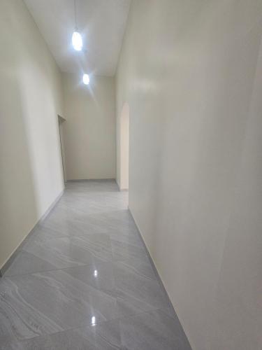 an empty hallway with white walls and a tile floor at White Mountain House in Sharīyah