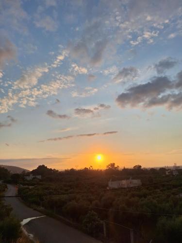 a sunset over a road with the sun in the sky at Solena in Tsikalariá