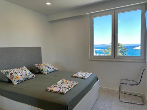 a bedroom with a bed with two pillows and a window at Palma Gena Makarska in Makarska