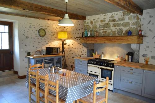 a kitchen with a table and a stove top oven at Gite Les Arrebourits 4 étoiles in Anères