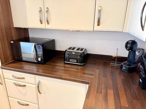 a kitchen with a microwave and a toaster oven on a counter at Charming 1BR Apartment In Heart of Cardiff Bay in Cardiff