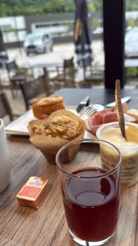 a table with a glass of wine and a plate of food at Hôtel Restaurant AKENA Molinges - La Brocatelle in Saint-Claude