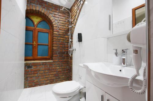a bathroom with a sink and a toilet and a window at Hotel Buzi Berat in Berat