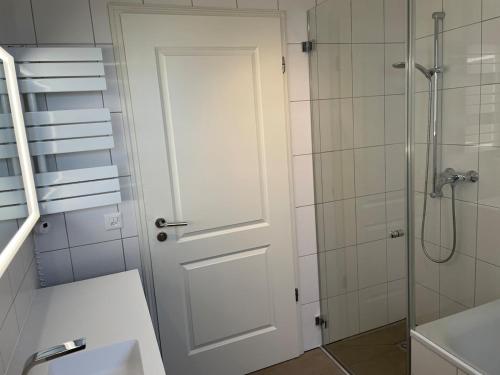 baño con ducha y puerta blanca en 2,5 Zimmer Einliegerwohnung in 3 Minuten zum Bodensee, en Dozwil