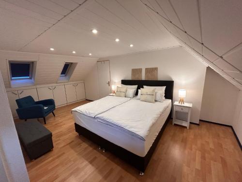 a bedroom with a large bed and a blue chair at Ferienhaus Niederrhein Kalkar - Traumhaus in klein am Niederrhein in Kalkar