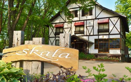 a house with a sign in front of it at Hakuba Skala Inn in Hakuba