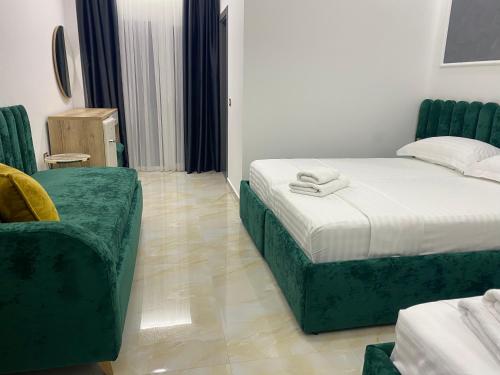 a bedroom with two beds and a green couch at Hotel Leodori 1 in Shëngjin