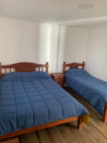 two beds in a room with blue sheets on them at Nogal in San Carlos de Bariloche