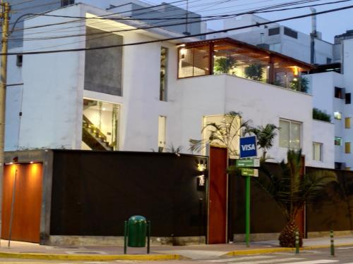 a white building with a palm tree in front of it at Ana Frank Boutique Hotel in Lima