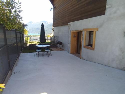 a patio with a table and umbrella next to a building at Gîte de la marmotte in Chevaline