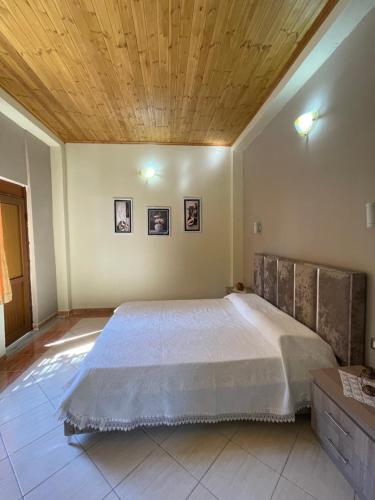 a bedroom with a large bed with a wooden ceiling at Harmonia Guest House in Vlorë