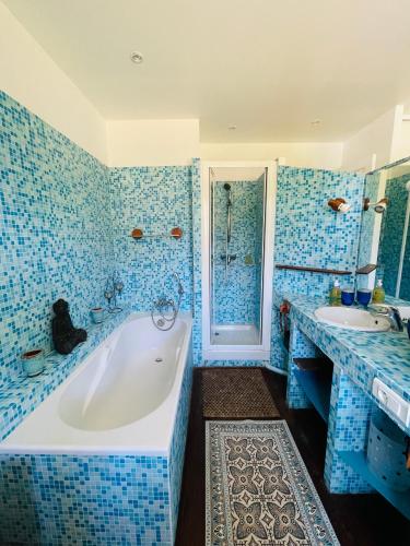 a blue tiled bathroom with a tub and a sink at Soimi, villa 4 chambres, petite piscine, plages a pieds in Pyla-sur-Mer