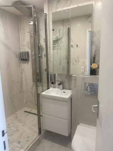 une salle de bain avec un lavabo, une douche et des toilettes dans l'établissement Vue, espace & confort Appartement 2 chambres avec terrasse & parking, aux portes de Paris, à Puteaux