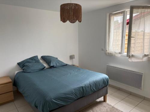 a bedroom with a bed with blue sheets and a window at Appartement cosy avec terrasse au calme in Urcuit