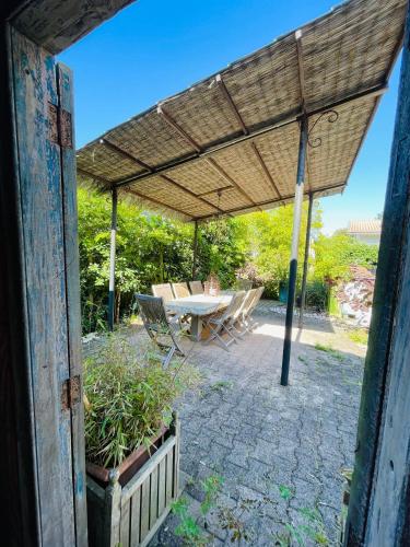 a patio with a table and chairs under a roof at Soimi, villa 4 chambres, petite piscine, plages a pieds in Pyla-sur-Mer