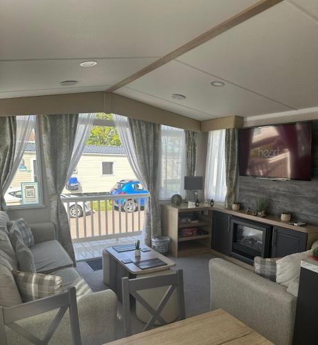 a living room with a couch and a tv at 3 bed presitage caravan Doniford Bay in Watchet