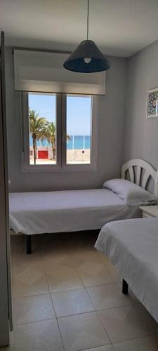 a bedroom with two beds and a window with the beach at salobreña primera linea de playa in Salobreña