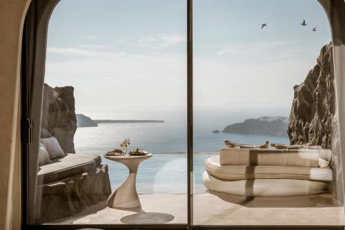 a room with a view of the ocean through a window at One of One Hotel in Imerovigli