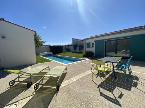un patio avec une table et des chaises et une piscine dans l'établissement La Villa du Platin, à La Flotte