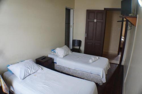 a hotel room with two beds and a television at Hotel Santo Antonio in Botucatu