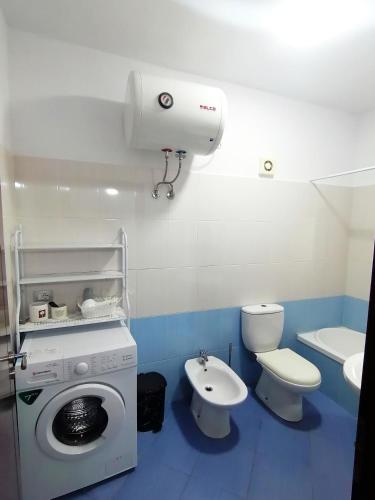 a bathroom with a washing machine and a toilet and a sink at Castle View Apartment in Gjirokastër