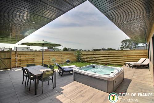 une terrasse avec un bain à remous, une table et des chaises dans l'établissement Villa le nid des dunes & spas - la villa, à Santec