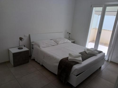 a white bedroom with a bed and a window at sosta modicana in Modica
