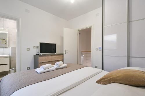a white bedroom with two towels on a bed at Villa Insula in Linardići
