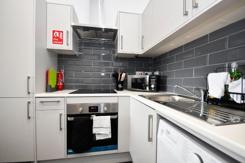 a kitchen with white cabinets and a stove and a sink at Modern & Compact 1 Bedroom Apartment in Bradford in Bradford