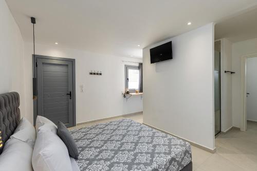 a bedroom with a bed and a tv on a wall at Chrysonisos Suites with Sunset & Seaviews near Kini in Ano Syros