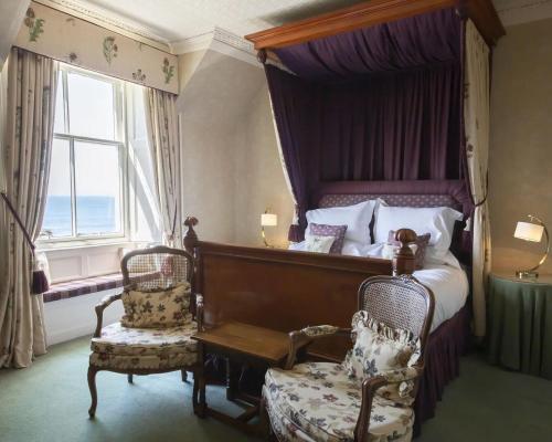 a bedroom with a bed and a chair and a window at Knockinaam Lodge in Portpatrick
