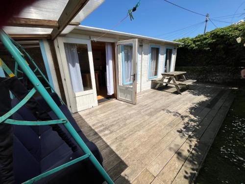 a house with a wooden deck with a picnic table at The Cabin Crooklets in Bude